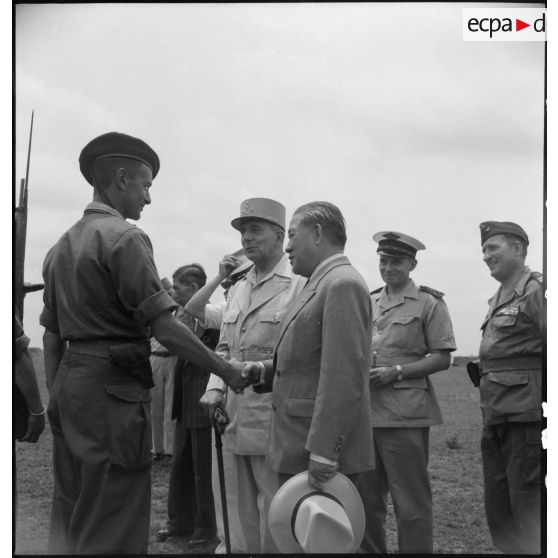 Le général de Lattre de Tassigny, commandant en chef en Indochine et Tran Van Huu, président du conseil des ministre de l'Etat du Vietnam; félicitent un soldat au cours d'une prise d'armes sur le terrain d'aviation de Vinh Yen.