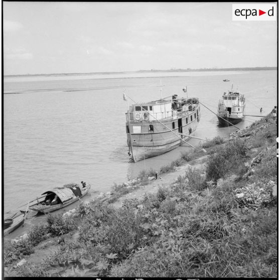 Sur les berges du fleuve Rouge, un bateau pour le transport des civils.