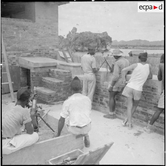 A l'intérieur de fortifications, les tirailleurs sénégalais armés de mortiers surveillent les environs du rocher de Ninh Binh que l'on distingue en arrière plan.