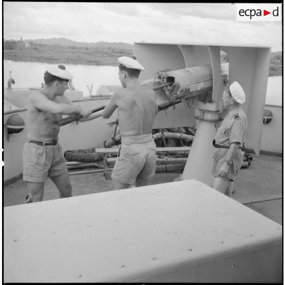 A bord d'un LCI, des soldats chargent une pièce d'un canon de 75 mm.