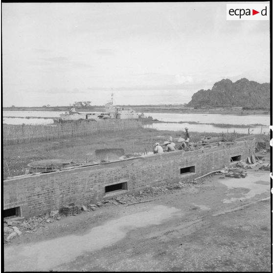 Un mur fortifié avec en arrière plan, la rivière Day et le rocher de Ninh Binh.