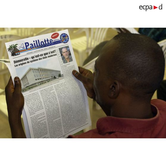 Un homme lit l'hebdomadaire La Paillote lors de la conférence de presse du conseiller communication de l'EUFOR.