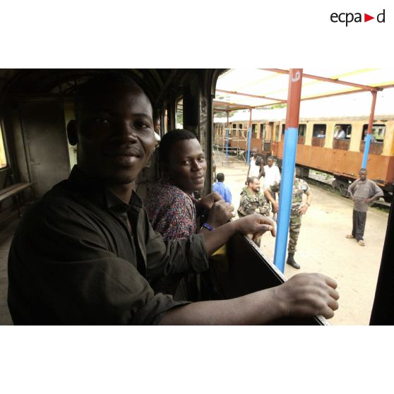 Congolais dans le couloir d'une voiture de train en gare.