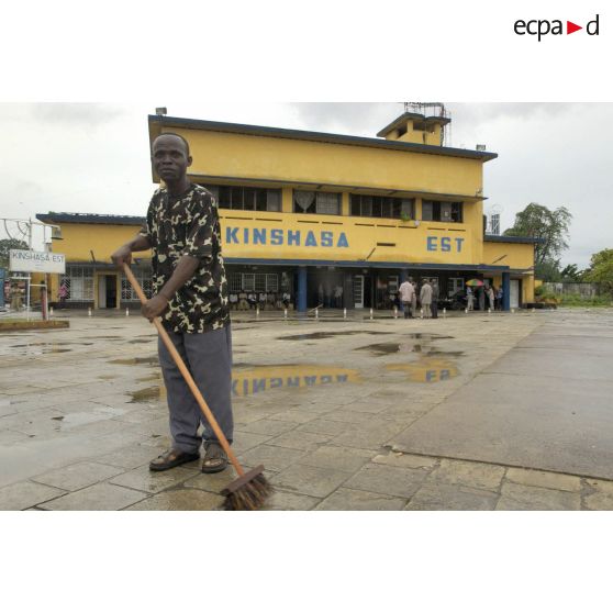 Un homme balaye sur le parvis de la gare de Kinshasa-Est.