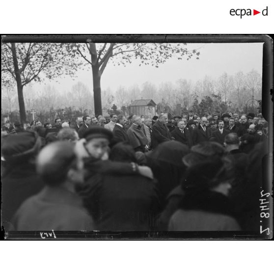 [La foule se recueille dans un cimetière.]