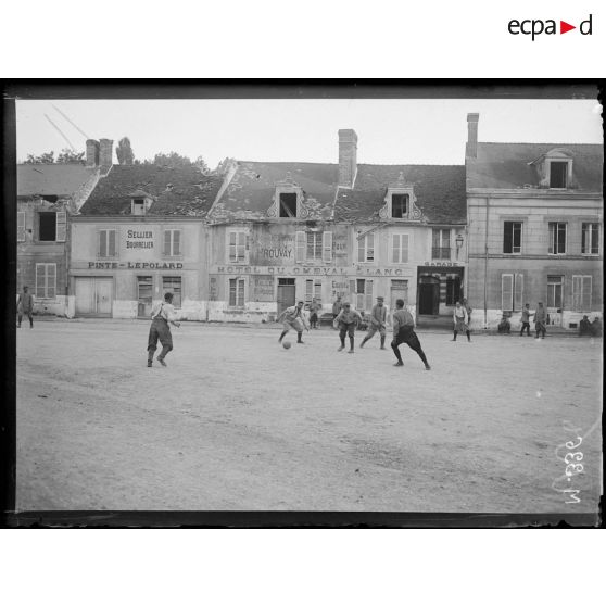 Des soldats participent à une partie de football dans les rues d'Hermonville. [légende d'origine]