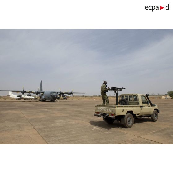 Un soldat malien sécurise le périmètre d'un avion-cargo Hercules C-130 H-30 de l'escadron de transport 2/61 Franche-Comté à bord de son pick-up sur l'aéroport de Bamako, au Mali.