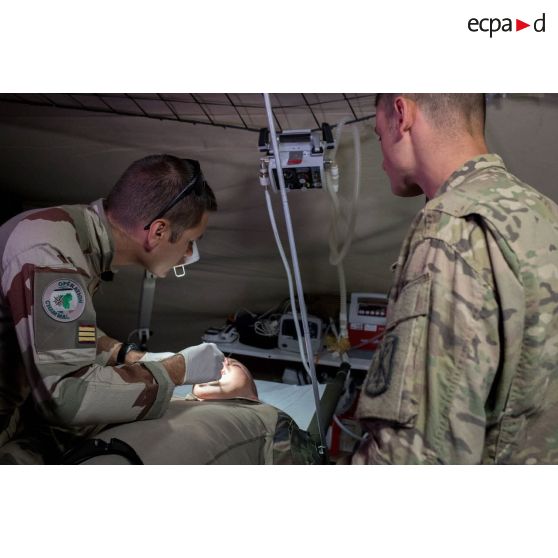 Un médecin des armées du SSA (Service de santé des armées) examine la bouche d'un artilleur français de la Task Force Wagram se plaignant de douleurs aux dents, en présence d'un aide soignant américain.