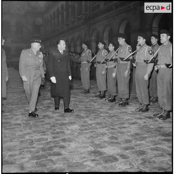 Aux Invalides, Pierre de Chevigné, secrétaire d'Etat à la Guerre, et le général de corps d'armée Magrin-Vernerey (dit Monclar), commandant les FTF ONU (Forces terrestres françaises de l'ONU), passent en revue les volontaires du 1er Bataillon Français des Nations Unies (Bataillon de Corée).