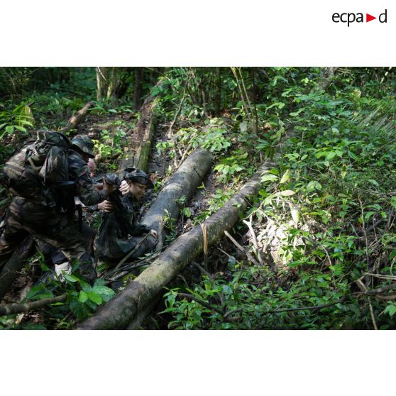 Le caméraman Morgan aide le capitaine Flora à se relever d'une chute lors de la traversée d'un pont lors d'une patrouille à Saint-Jean-du-Maroni, en Guyane française.