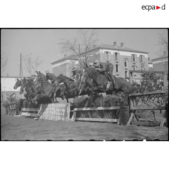 Des sous-officiers du 7e régiment de chasseurs à cheval (RCC) et leurs montures franchissent des obstacles.