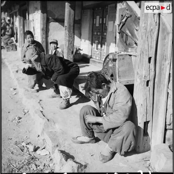 Groupe de Coréens devant une habitation dans un village.