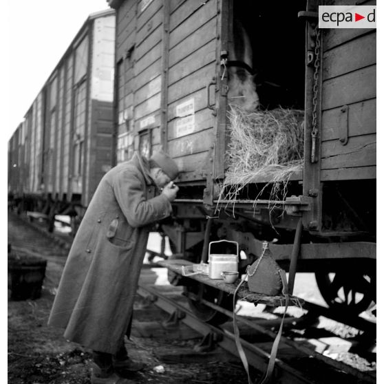 Un soldat mange debout près d'un wagon.