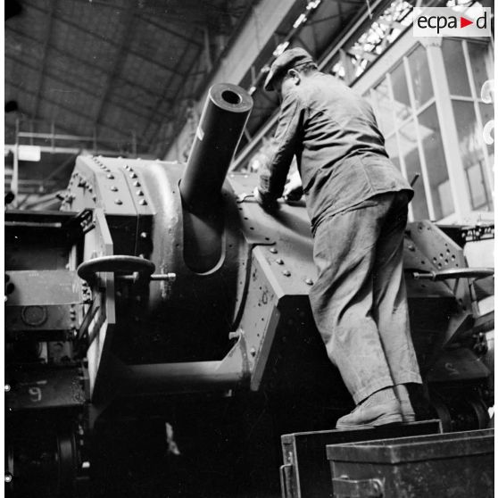 A l'atelier d'Issy-les-Moulineaux un ouvrier pose des rivets sur le masque du canon de 75 mm SA modèle 1935.