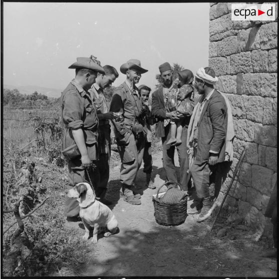 Le capitaine officier SAS (section administrative spécialisée) de Tigzirt) offrant un foulard à une enfant algérienne de Tala'n Taghrast.