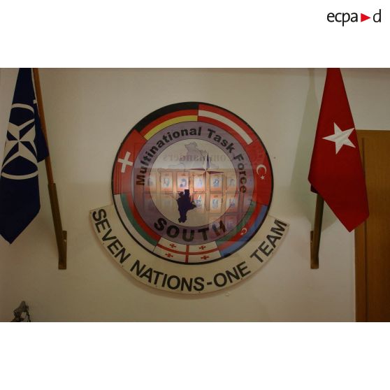 Emblème de la Multinational task force South et devise "seven nations, one team" (7 nations, 1 équipe).