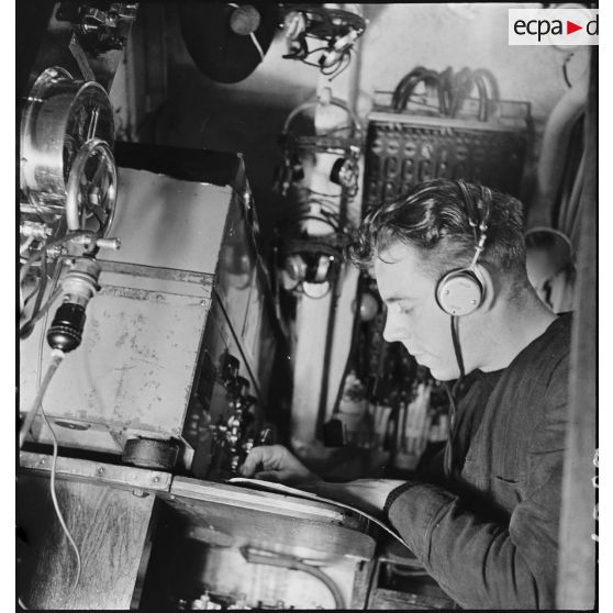 L'opérateur radio du sous-marin des FNFL (Forces navales françaises libres) la Minerve envoie ou réceptionne des messages depuis le poste central radio, au cours d'un exercice.