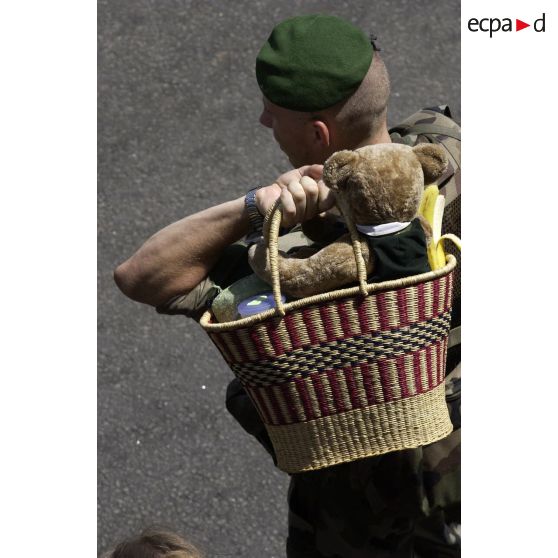 Un légionnaire transporte un sac contenant un ours en peluche d'enfant appartenant à des ressortissants évacués à l'aéroport international d'Abidjan.