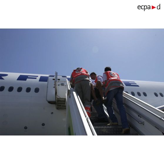 Des personnels de la Croix-Rouge transportent un ressortissant blessé évacué sur la passerelle de l'avion Boeing 777 d'Air France lors de l'embarquement à l'aéroport international d'Abidjan.