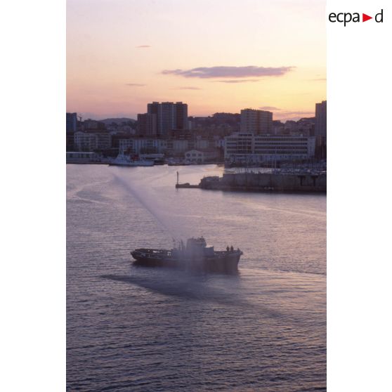 Un bateau-pompe salue l'arrivée du  ferry affrété Danielle Casanova à l'aube dans la rade de Toulon.