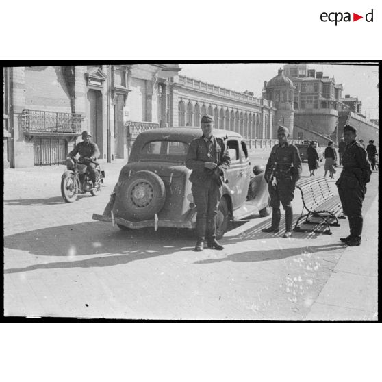 Rhe Feldy. [Un groupe de soldats allemands devant une automobile et un long bâtiment]. [Description en cours]