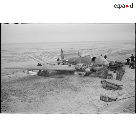 Des civils inspectent les nacelles moteur d'un avion de bombardement Heinkel He-111 du KG-26, endommagé après un atterrissage forcé sur la côte allemande. Ce bombardier Heinkel He 111H 2.KG26 de retour de Scapa-Flow a fait un atterrissage sur une plage à l'ouest de Cuxhaven (20 mars 1940) à  bord, un seul aviateur décède lors de l'atterrisage forcdé, il s'agit de Hans Baehr.