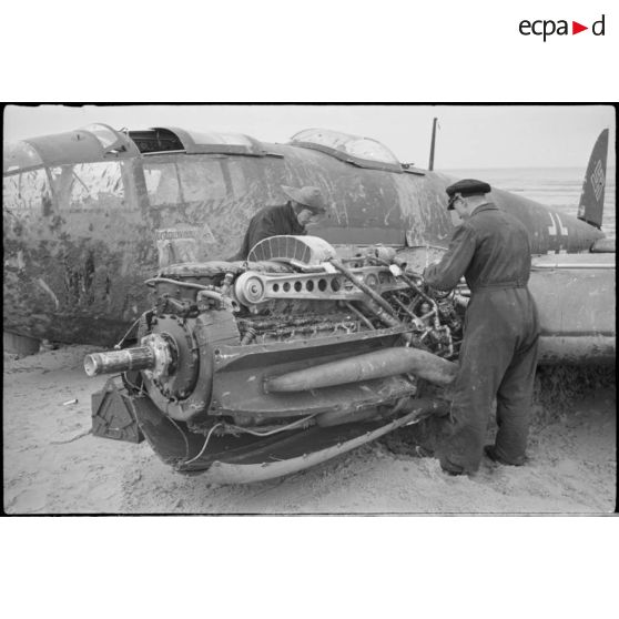 Des civils inspectent les nacelles moteur d'un avion de bombardement Heinkel He-111 du KG-26, endommagé après un atterrissage forcé sur la côte allemande. Ce bombardier Heinkel He 111H 2.KG26 de retour de Scapa-Flow a fait un atterrissage sur une plage à l'ouest de Cuxhaven (20 mars 1940) à  bord, un seul aviateur décède lors de l'atterrisage forcdé, il s'agit de Hans Baehr.