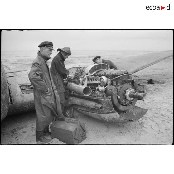 Des civils inspectent les nacelles moteur d'un avion de bombardement Heinkel He-111 du KG-26, endommagé après un atterrissage forcé sur la côte allemande. Ce bombardier Heinkel He 111H 2.KG26 de retour de Scapa-Flow a fait un atterrissage sur une plage à l'ouest de Cuxhaven (20 mars 1940) à  bord, un seul aviateur décède lors de l'atterrisage forcdé, il s'agit de Hans Baehr.