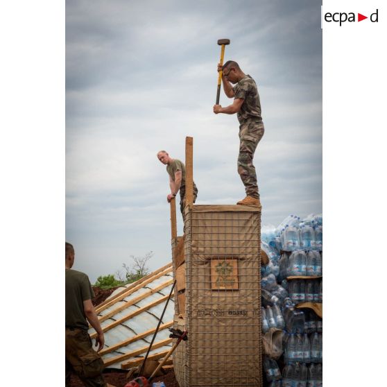 Soldats du 3e RG consolidant la charpente du pilier d'un bâtiment au moyen d'une masse, lors d'une intervention auprès du GTIA (groupement tactique interarmes) Turco, afin de procéder aux réparations des installations de l'aérodrome de Bambari détruites suite au passage d'une tempête.