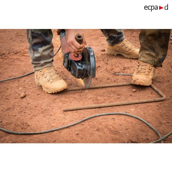 Soldats du 3e RG ajustant un arc metallique destiné à l'armature d'un bâtiment au moyen d'une scie circulaire, lors d'une intervention auprès du GTIA (groupement tactique interarmes) Turco, afin de procéder aux réparations des installations de l'aérodrome de Bambari détruites suite au passage d'une tempête.