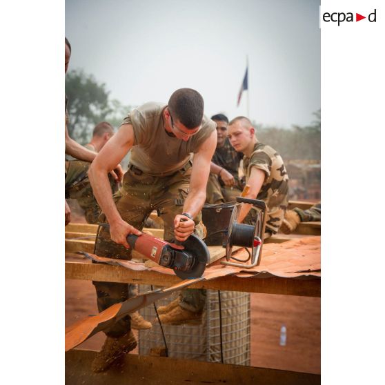 Soldats du 3e RG consolidant la toiture d'un bâtiment au moyen d'une scie circulaire, lors d'une intervention auprès du GTIA (groupement tactique interarmes) Turco, afin de procéder aux réparations des installations de l'aérodrome de Bambari détruites suite au passage d'une tempête.