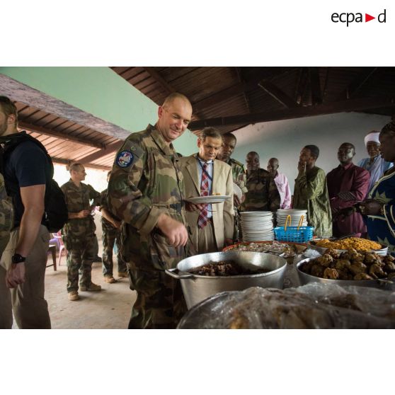 Le général de brigade Éric Bellot des Minières, commandant la force Sangaris, déguste un mets local lors du repas donné en clôture de la cérémonie de réouverture du marché de Bambari.