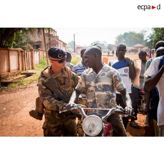 Un tirailleur de la compagnie Rouge du 1er RT du GTIA (groupement tactique interarmes) Turco contrôle un civil à mobylette, lors d'une mission de contrôle sur un check-point établi sur l'axe du marché central de Bambari, en compagnie des casques bleus de la MINUSCA (mission multidimensionnelle intégrée des Nations Unies pour la stabilisation en Centrafrique).