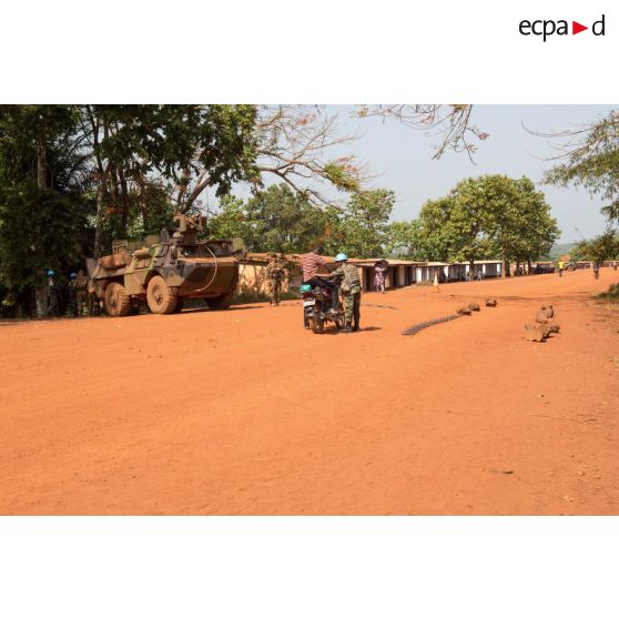 Un casque bleu de la MINUSCA (mission multidimensionnelle intégrée des Nations Unies pour la stabilisation en Centrafrique) contrôle des civils à mobylette, lors d'une mission de contrôle sur un check-point établi sur l'axe du marché central de Bambari, en compagnie des tirailleurs de la compagnie Rouge du 1er RT du GTIA (groupement tactique interarmes) Turco.