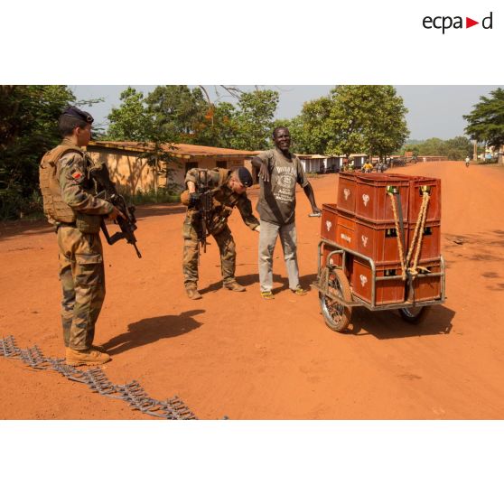 Tirailleurs de la compagnie Rouge du 1er RT du GTIA (groupement tactique interarmes) Turco contrôlant un civil, lors d'une mission de contrôle sur un check-point établi sur l'axe du marché central de Bambari, en compagnie des casques bleus de la MINUSCA (mission multidimensionnelle intégrée des Nations Unies pour la stabilisation en Centrafrique).