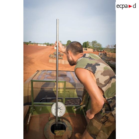 Un soldat du détachement opérationnel du SEA (Service des essences des armées) auprès du GTIA (groupement tactique interarmes) Turco, mesure au moyen d'une règle la composition chimique du carburant en prévision d'un ravitaillement depuis un camion-citerne Scania CCP 10 (camion-citerne polyvalent de 10 mètres cube).