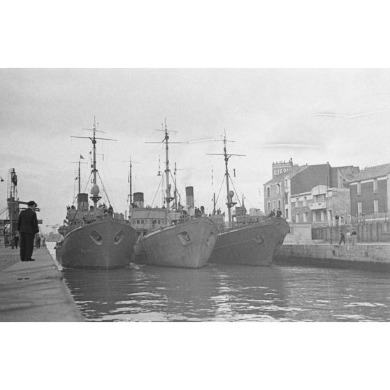 Dans le port de Saint-Nazaire, des dragueurs de mines protègent des sous-marins allemands peu avant leur appareillage.