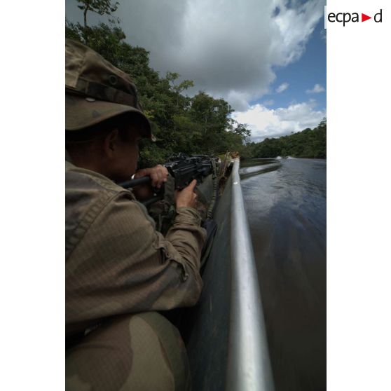 Un stagiaire patrouille à bord d'une pirogue armé d'une mitrailleuse FN Minimi sur le fleuve Approuague à Régina, en Guyane française.