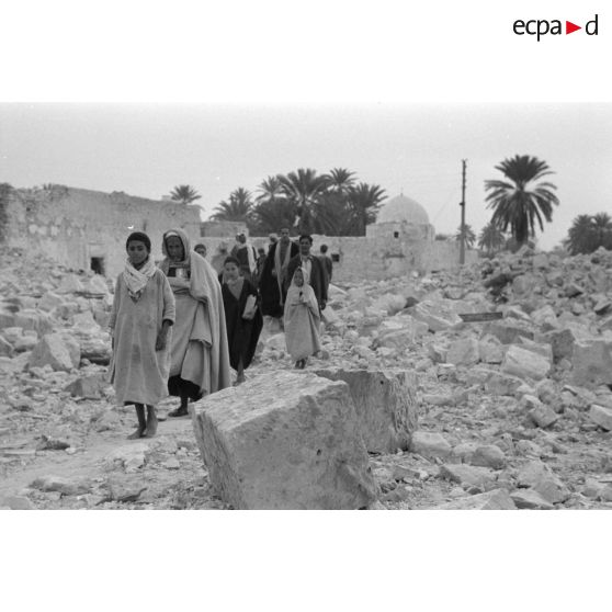 Dans Gafsa en ruines, la population, hommes et enfants, parcourt les ruines.