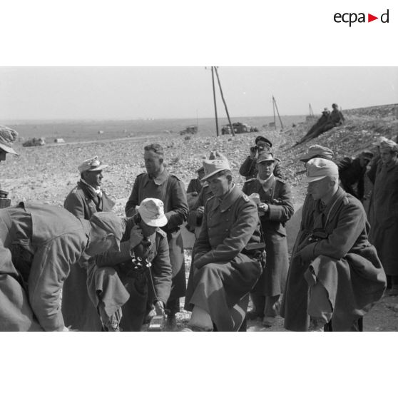 Un groupe d'officiers entoure un téléphone de campagne, à gauche, au second plan, le colonel (Oberst) Fritz Bayerlein.