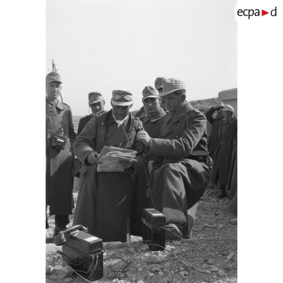 Le colonel (Oberst) Fritz Bayerlein, entouré d'officiers de son état-major, prend une communication téléphonique.