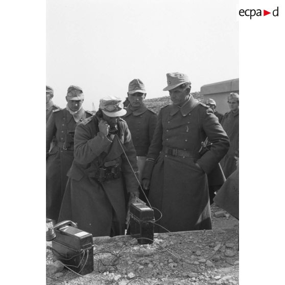 Le colonel (Oberst) Fritz Bayerlein, entouré d'officiers de son état-major, prend une communication téléphonique.