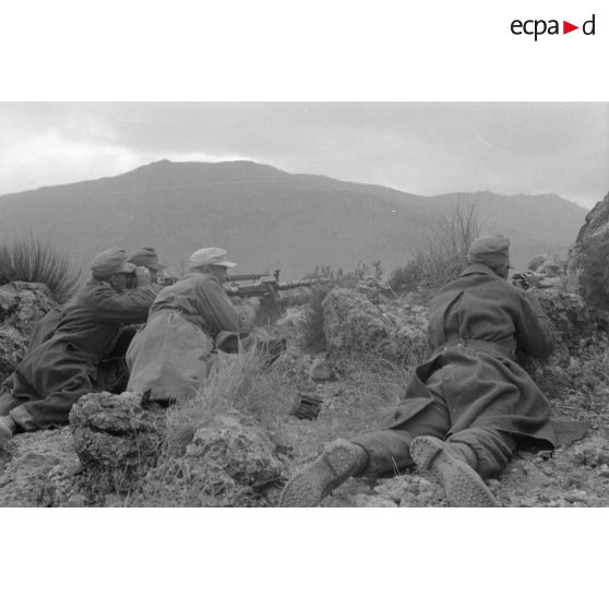 Un groupe de soldats est allongé au sommet d'une colline, tir d'une mitrailleuse MG-34.