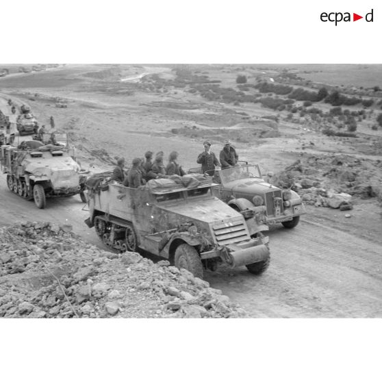 Le maréchal Rommel et l'Oberst Bayerlein, debout dans une voiture Kfz-21, longent la colonne de véhicules.