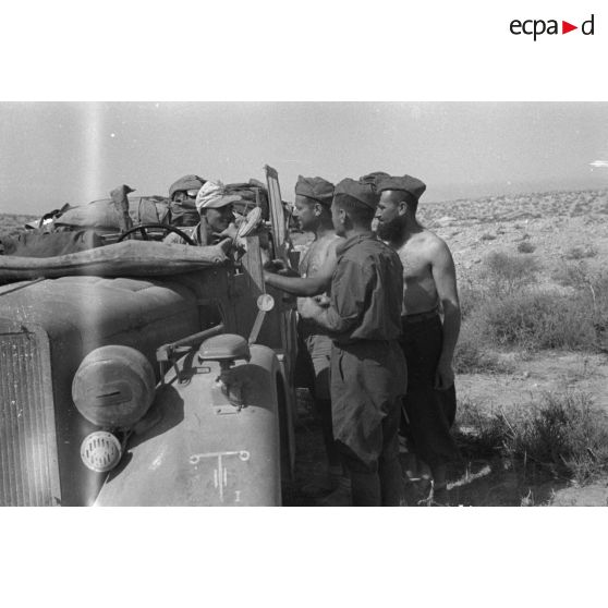 Des soldats allemands du Panzer.Artillerie Regiment 155 (Pz.Art.Rgt-155) installés dans une voiture Kfz-16 discutent avec des italiens du 24e RAA.