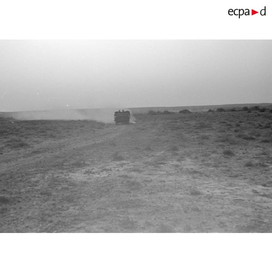 Une voiture Horch Kfz-18 roule sur une piste en provoquant un nuage de poussière.