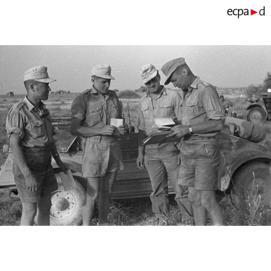 Un sous-officier distribue du courrier à trois de ses hommes devant une voiture Kübelwagen.