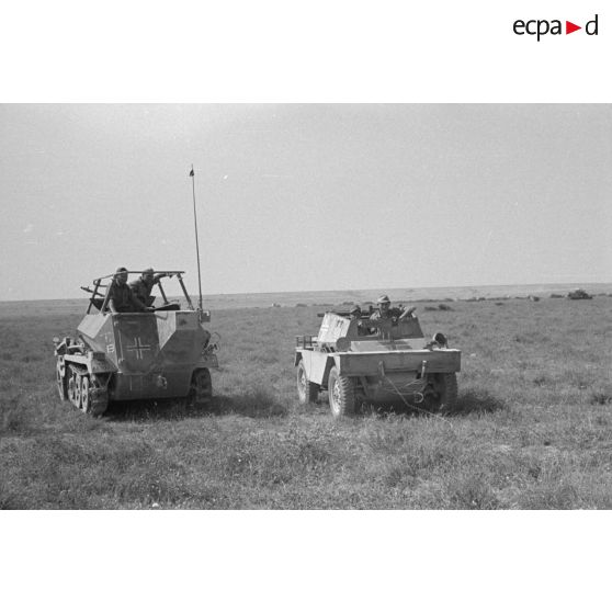 Un semi-chenillé Sd.Kfz 250/3 de la 3e batterie du Panzer Artillerie Regiment 155 (Pz.Art.Rgt-155) à côté d'un véhicule de prise Daimler Scout Car.