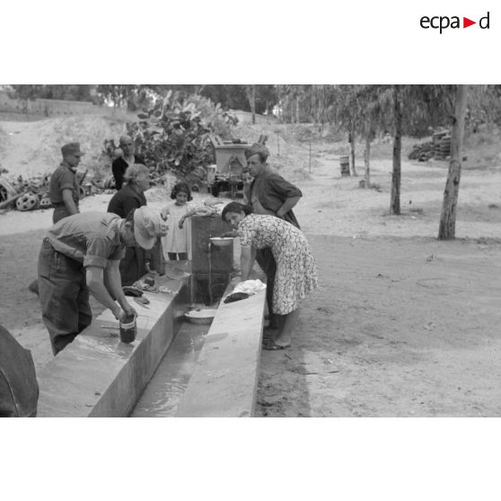 Des mécaniciens du Nachschubkolonne Abteilung 909 au lavoir en compagnie de civils.