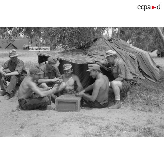 Des soldats du Nachschubkolonne Abteilung 909 jouent aux cartes, un panneau baptisé Schwalbennest (nid des hirondelles).